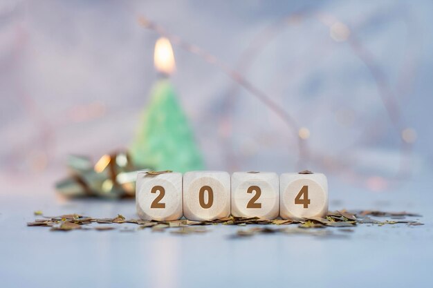 Photo new year holiday background inscription on wooden cubes of the number 2024 with bright glowing lights