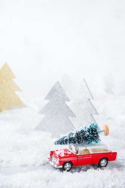 年末年始のコンセプト雪の森でクリスマスツリーを運ぶ赤いおもちゃの車お祭りの装飾が施されたコピースペースグリーティングカード