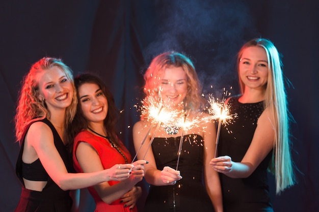 New year party, celebration and holidays concept - group of friends having fun with sparklers.