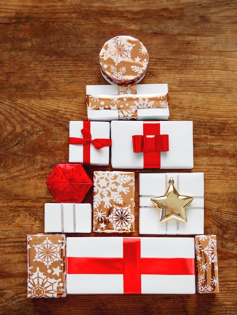 Foto regali di capodanno a forma di albero di natale su tavolo di legno regali in carta bianca e dorata