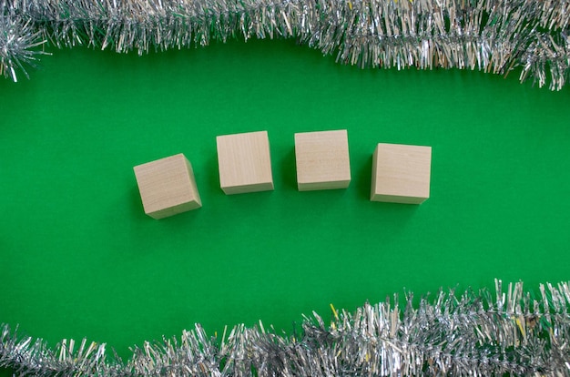 Photo new year's card template wooden cubes for the number of the year tinsel on a green background