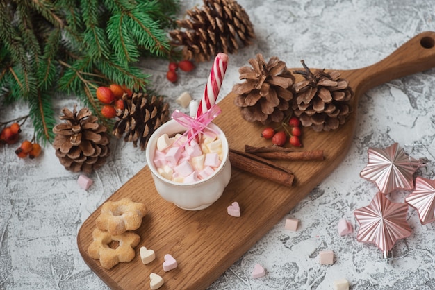 New Year's or Christmas composition cup with marshmelow on a wooden stand with cookies and candy among spruce green branches