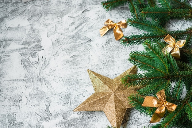 새해 또는 크리스마스 구성은 가문비나무 녹색 가지와 새해, 반짝이는 황금색 장난감, 밝은 질감 배경의 별입니다. 플랫 레이, 레이아웃, 프레임, 텍스트 위치, 복사 공간, 상단 보기