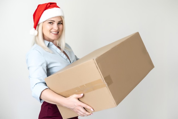 알아볼 수 있는 상자에 담긴 새해 크리스마스 소포, 배달 온라인 상점, 빨간 산타클로스 모자를 쓴 예쁜 여성이 상자 더미를 들고 있습니다. 흰색에 격리.