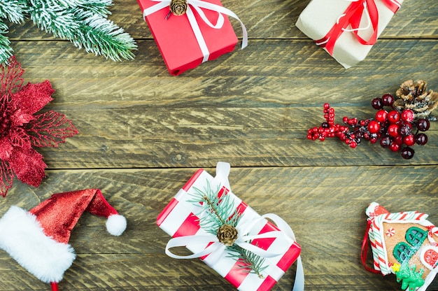 New Year's Christmas wooden background with traditional decorations on it. holiday boxes, red flower, santa hat.