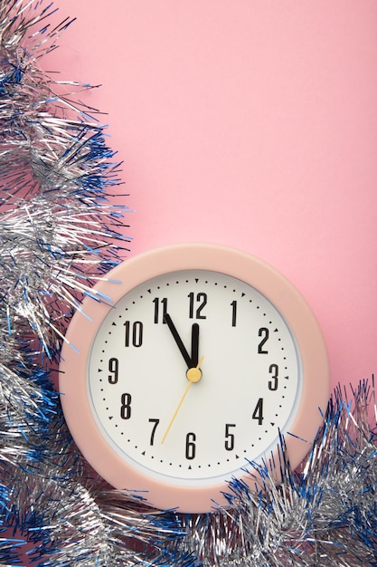 New Year's clock decorated with christmas tinsel Celebration Concept for New Year Eve Vertical photo