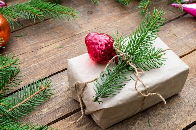 New Year's composition of Christmas tree decorations and spruce branches. Gift wrapped in craft paper from a sprig of spruce.