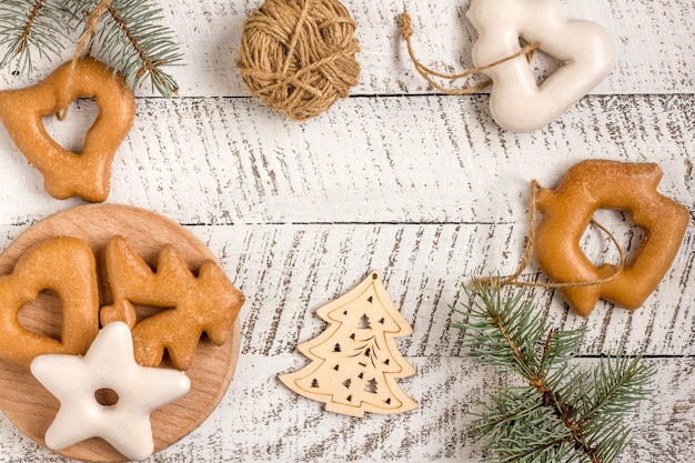 New Year's composition. Gingerbreads, gift wrapped in paper and Christmas decorations on a white wooden background. Christmas, winter, new year concept. Flat lay, top view with copy space.