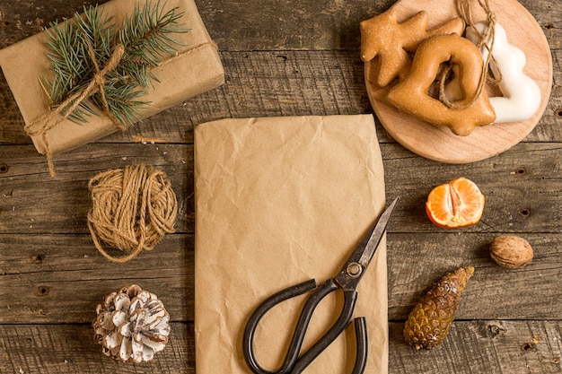 New Year's composition. Gingerbreads, gift wrapped in paper and Christmas decorations on a wooden background. Christmas, winter, new year concept. Flat lay, top view.