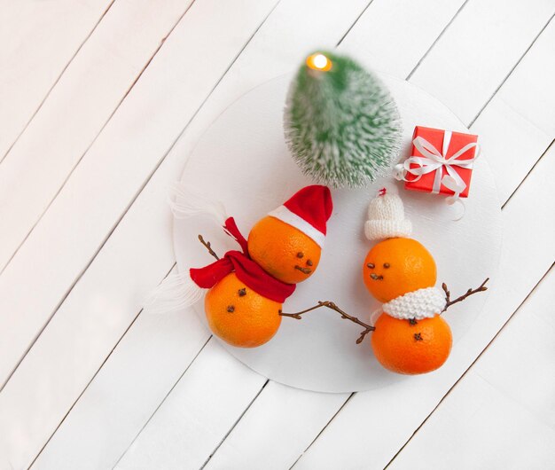 Foto composizione di capodanno bambini di neve mandarino con cappelli di babbo natale decorazione carina di capodanno vista superiore