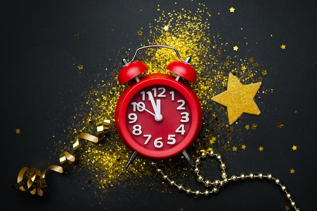 New year's composition with a red clock on a black surface