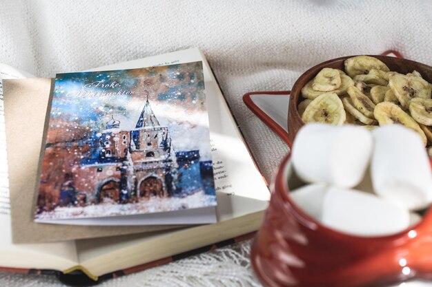 Photo new year's eve background santa claus mug with marshmallows christmas cookies open book