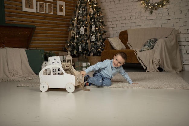 On new year\'s eve the boy is playing with a wooden car he is\
happy because the new year holiday is coming soon everything is\
decorated with bright lights