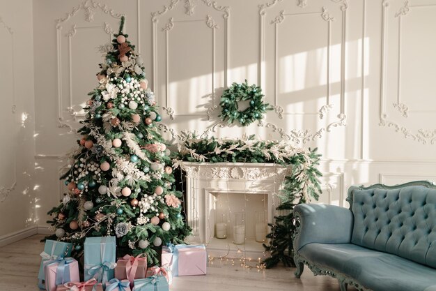 New Year's gifts in designer paper and bright ribbons under the Christmas tree on the floor on New Year's Eve Christmas tree decorated with toys stands near the fireplace