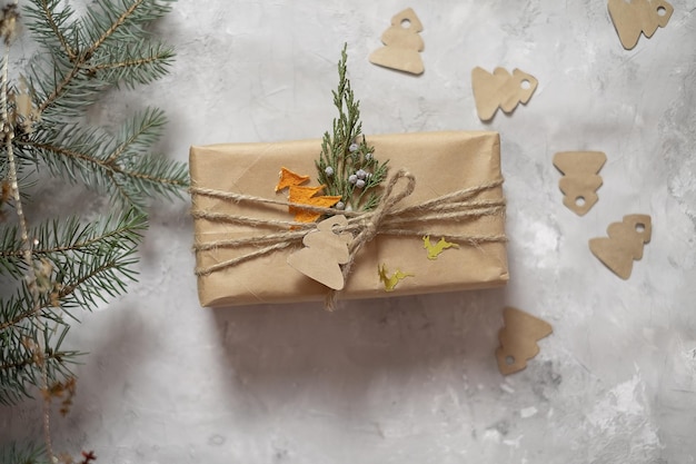 Новогодние подарки, упакованные в крафт-бумагу, лежат на кровельном листе на сером фоне