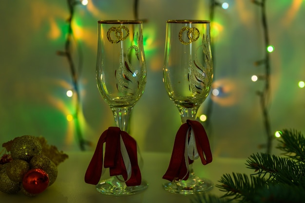 New Year's glasses on the background of a luminous garland in green.