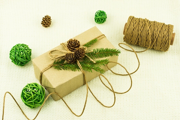 New year\'s holiday box with a gift, decorated with your own\
hands and wrapped in kraft paper. green branches of spruce, cones,\
decorative balls.