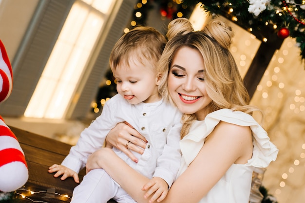 Ritratto del nuovo anno di una giovane madre attraente con un giovane figlio con un bar di natale. anno nuovo e concetto di natale