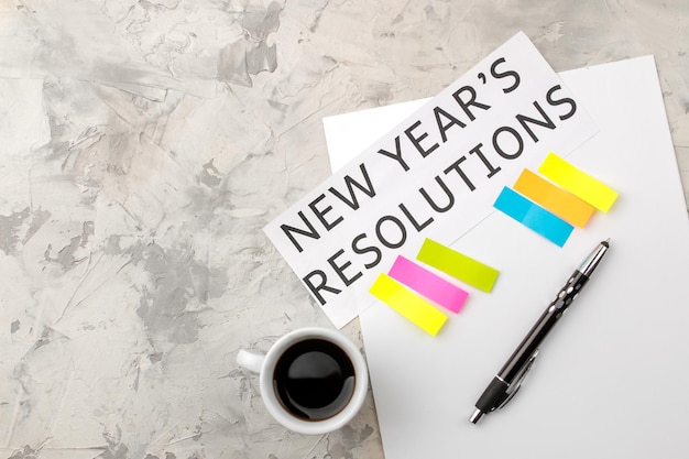 Photo new year's resolution. text on paper with color stickers and a cup of coffee on a light background.