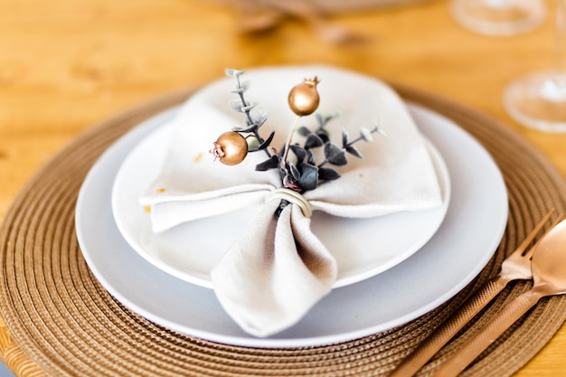 New Year table decor. A white napkin with decor lies on the plate, under the plate there is a bronze-colored countertop.Photo