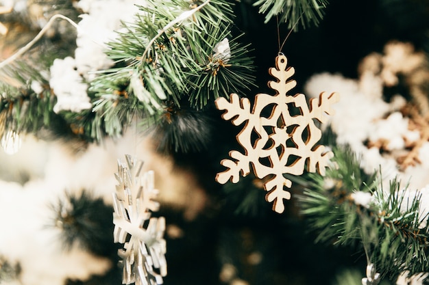 New year toys in the shape of wooden snowflakes on christmas tree. New year decorations