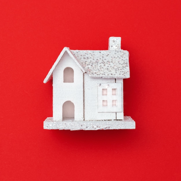 Новогодний деревянный игрушечный домик на красной бумаге