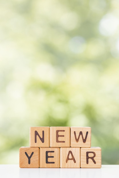 Photo new year word in wooden cubes on green summer background