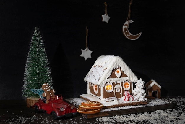 New years composition gingerbread house gingerbread cookies toy\
car artificial christmas tree