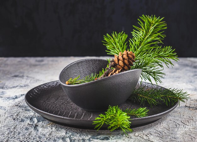 New Years composition for table decoration with fir branches and cones in black dishes festive decor