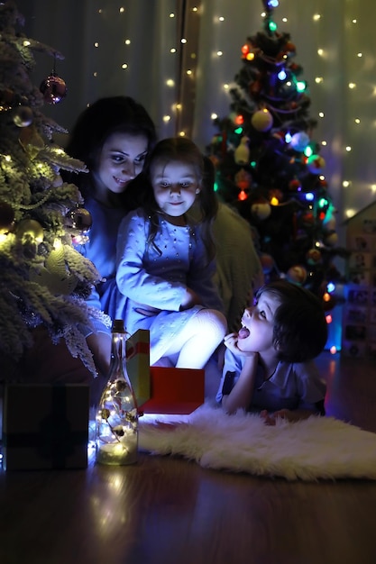 Vigilia di capodanno. la casa è decorata per le vacanze. albero di natale elegantemente vestito con una ghirlanda e una famiglia con regali e una sorpresa.