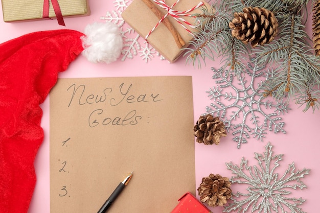 새해 목표 2019년 새해 장식과 밝은 분홍색 배경에 펜이 있는 종이에 텍스트.