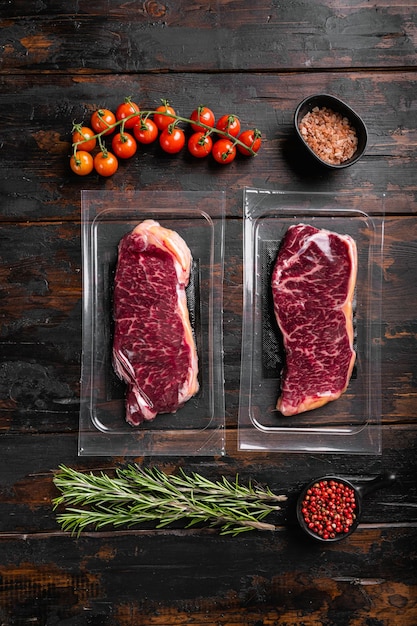 New York beef steak cut in plastic pack set, on old dark  wooden table background, top view flat lay