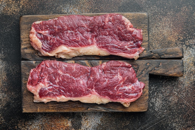 New york beef steaks, on old dark rustic background, top view flat lay