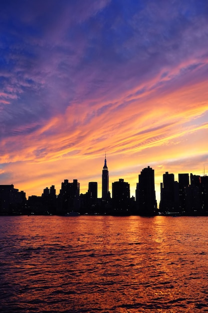 Panorama della siluetta del centro di manhattan di new york city al tramonto con i grattacieli ed il cielo variopinto sopra l'east river