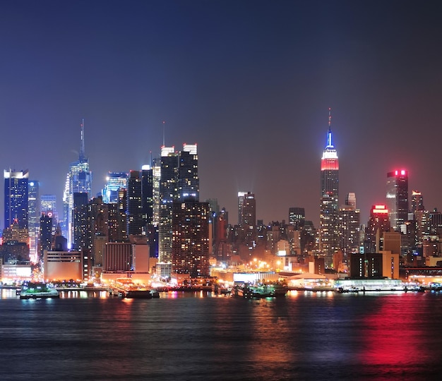 New York City Manhattan midtown skyline 's nachts met wolkenkrabbers verlicht over Hudson River met reflecties.