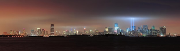 New York City Manhattan skyline van de binnenstad panorama 's nachts met vrijheidsbeeld en lichtstralen ter nagedachtenis van 11 september, gezien vanaf de waterkant van New Jersey.