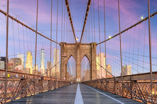 뉴욕 브루클린 다리 산책로(Brooklyn Bridge Promenade)에서 새벽 맨해튼(Manhattan) 스카이라인을 마주하고 있습니다