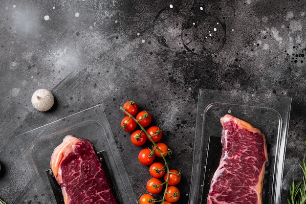 New York steak in vacuum pack set, on black dark stone table background, top view flat lay, with copy space for text