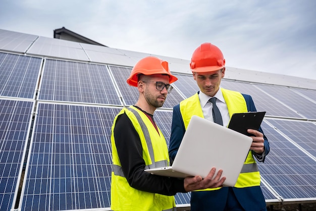 New young in helmets and special clothing are discussing a plan\
to install solar panels