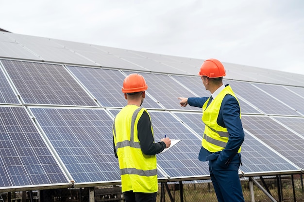 New young professionals in professional helmets and special clothing are discussing a plan to install solar panels. The concept of installing green electricity