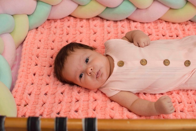 Newborn 2monthold girl sleeps in a crib on a pink knitted blanket the morning of the child The concept of children's goods Happy childhood of a healthy child