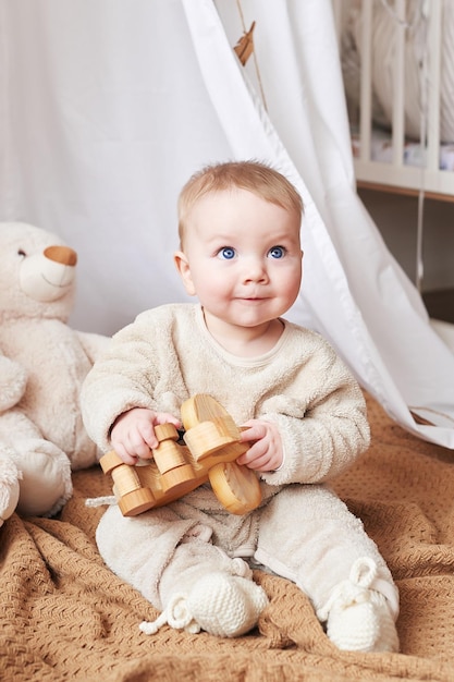 生まれたばかりの6か月の男の子が座って、知育おもちゃで遊んでいます。幸せな母性と父性。産科病院およびクリニック。父と母の日。幼児期の発達。