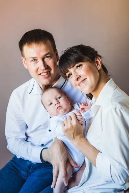 Newborn in the arms of the mother, next to dad, family and baby, tiny baby