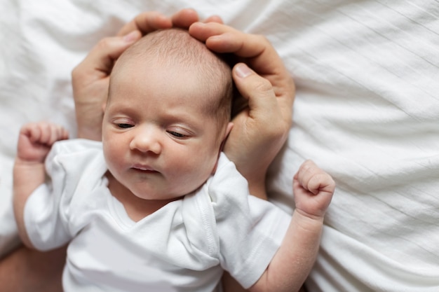 Newborn baby in the arms of the dad at home. Clous up portrait of infant baby in big husband's hands. The health of the newborn. Fatherhood and child care concept