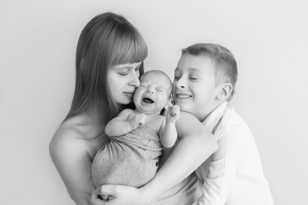 newborn baby in the arms of mother and older child, black and white photo, monochrome. parental care