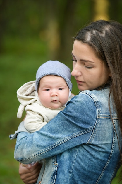 Newborn baby in the arms of mother on the street. a young mother is holding a baby in her arms in the street