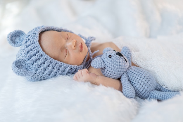 Foto neonato in cappello dell'orso che dorme sul letto di pelliccia