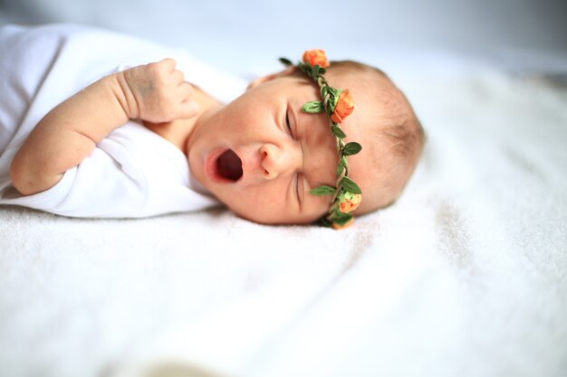 новорожденный ребенок на кровати зевая.