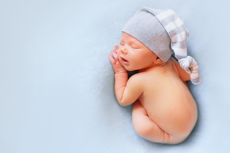 Photo newborn baby boy in the bonnet sleeping on the light blue background