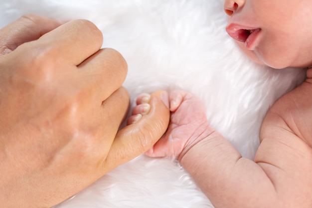 Newborn baby boy holding little finger of father's hand